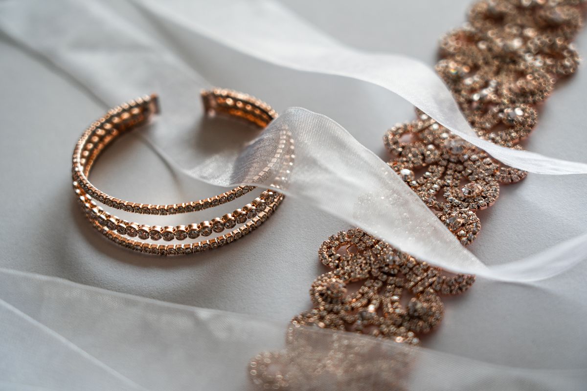 Pulseira e faixa com brilho cromado sobre tecido claro, detalhe de acabamento
